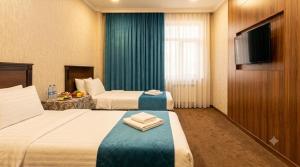 a hotel room with two beds and a flat screen tv at Hotel Usmoon in Tashkent