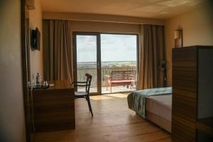 a hotel room with a bed and a desk and a balcony at Bakucha Vineyard Hotel ve Spa in Lüleburgaz +18 photos