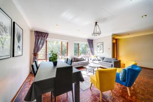 a living room with a table and yellow chairs at 18 Goethe in Secunda