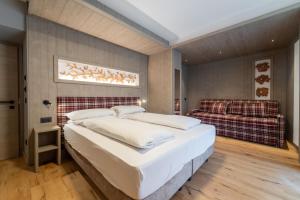 a bedroom with two beds and a couch at Albergo Maggiorina in Ledro