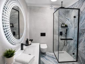 a bathroom with a shower and a sink and a mirror at WHITE TITANIC LUXURY Sea View & Studios in Mamaia Sat/Năvodari +93 photos