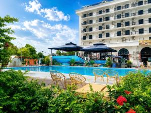 a pool with chairs and umbrellas in front of a hotel at ATOUR Phoenix Hotel in Bắc Ninh