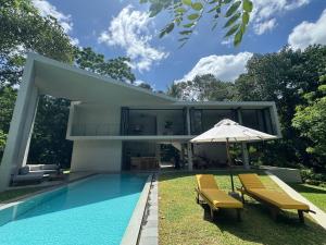 a house with a pool and two chairs and an umbrella at The Sevana in Talalla South