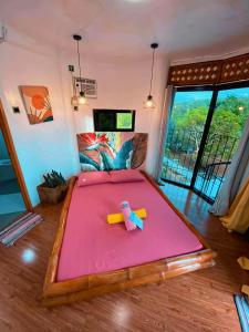 a bedroom with a large bed with a pink sheet at La Provinzia Exclusive Use - 3 Air-Conditioned Rooms 3 Fan Cooled Huts Good for 12 People in Camotes Islands