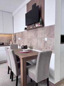 a dining room table with chairs and a television on a wall at Monte LUX 10 in Kopaonik