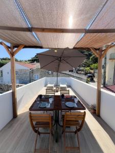 a wooden table with chairs and an umbrella on a roof at JUNKEIRA - Casa, Douro e Campo in Junqueira