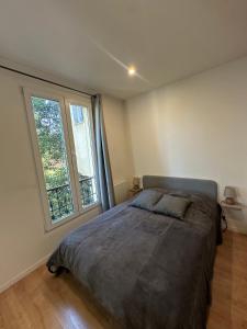 a bedroom with a bed and a large window at La lumière d'Issy in Vanves
