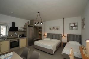 a bedroom with two beds and a kitchen with a table at Onar Sifnos by the sea in Cherronisos +27 photos