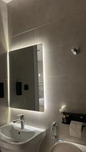 a white bathroom with a sink and a mirror at Sukoon in Dammam +4 photos