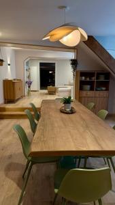a dining room with a wooden table and green chairs at Les 4 Horizons in Romorantin
