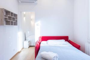 a red bed in a white room with a white bedspread at Garisenda, Bologna by Short Holidays in Bologna