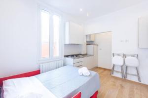 a kitchen with a bed and two white chairs in a room at Garisenda, Bologna by Short Holidays in Bologna