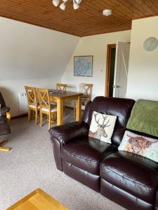 a living room with a leather couch and a table at West Haven Lodge in Aultbea