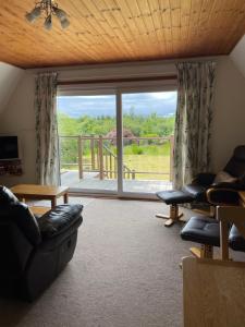 a living room with couches and a large window at West Haven Lodge in Aultbea +5 photos