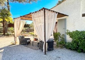 a patio with a gazebo with a chair and a table at Villa Les Lucioles - Chambre indépendante - Piscine privative - Petit déjeuner - Parking in Valbonne