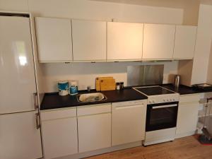 a kitchen with white cabinets and a sink at Satellit lejligheder Vejle C in Vejle +6 photos