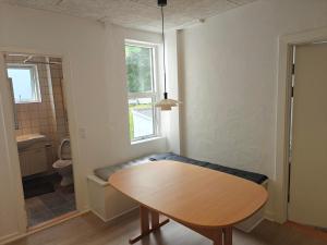 a room with a table and a bathroom with a toilet at Satellit lejligheder Vejle C in Vejle