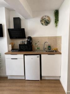 a kitchen with white cabinets and a sink at Escale Tropicale in Lectoure