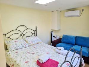 a bedroom with a bed and a blue couch at The Witterings Bed and Breakfast in Chichester