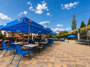 a patio with tables and chairs with blue umbrellas at SPA Resort HeRICH in Bukovel