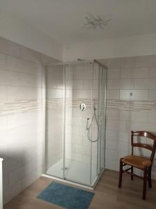 a shower with a glass door next to a chair at Agriturismo al rosari in Aquiléia