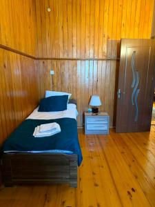 a bedroom with a bed with a wooden wall at Baias Wine in Bagdatʼi