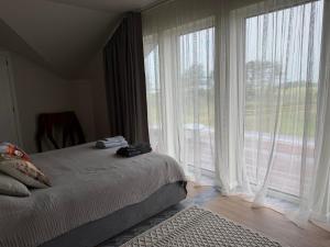 ein Schlafzimmer mit einem Bett und einem großen Fenster in der Unterkunft Skrablas Boutique Hotel in Rucava + 59 Fotos
