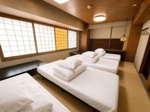 three beds in a room with three windows at Osaka Guesthouse Sakura in Osaka