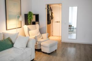 a living room with a white couch and a chair at Zentrale City Apartments in Oldenburg
