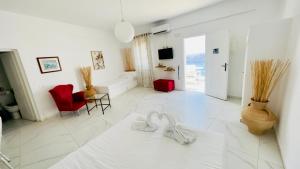 a white living room with red chairs and a white floor at Loucas on the Cliff in Fira
