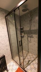 a shower with a glass door in a bathroom at Le Gîte des Jardins d'Ispahan in Prignac-et-Marcamps
