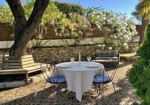 a table with a white table cloth and chairs and a tree at Villa Les Lucioles - Chambre indépendante - Piscine privative - Petit déjeuner - Parking in Valbonne