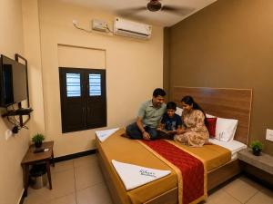 a man and a woman and a child sitting on a bed at Nathan's Residency in Tiruchirappalli