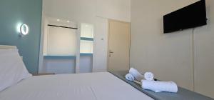 a bedroom with a white bed with towels on it at Sidari Escapes By The Beach in Sidari