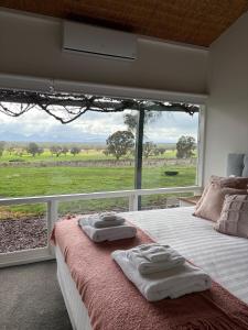a bedroom with a large window with towels on a bed at Bunnugal House in Dunkeld