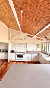 a large kitchen with white cabinets and a wooden ceiling at Bunnugal House in Dunkeld