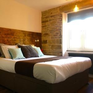 a bedroom with a large bed with a brick wall at Over Under Cottage in Holmfirth