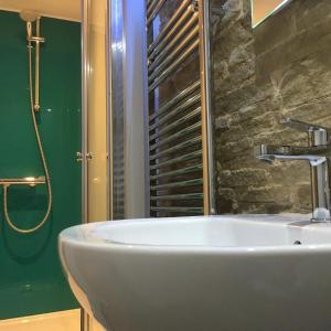 a white sink in a bathroom with a green wall at Over Under Cottage in Holmfirth +6 photos