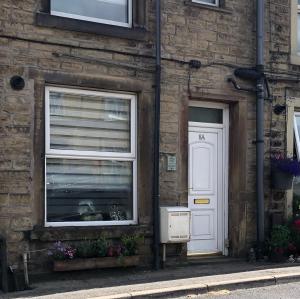 a brick building with a window and a white door at Over Under Cottage in Holmfirth