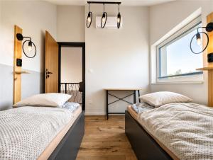 two beds in a bedroom with a window at Skośne Domki 2 in Chmielno