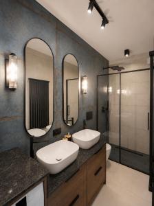 a bathroom with two sinks and two mirrors at Skośne Domki 2 in Chmielno