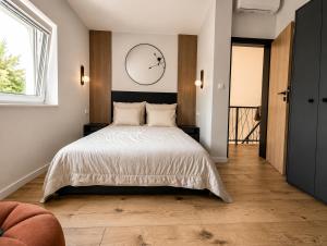 a bedroom with a bed and a clock on the wall at Skośne Domki 2 in Chmielno