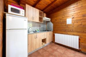 a kitchen with wooden cabinets and a white refrigerator at Cabañas Cortijo el Helao in Pozo Alcón +28 photos