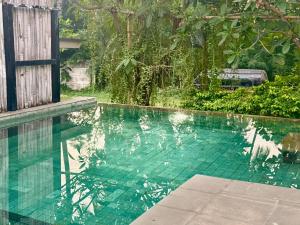 a swimming pool with turquoise water and trees at Lombok House Mentigi in Teluknarat