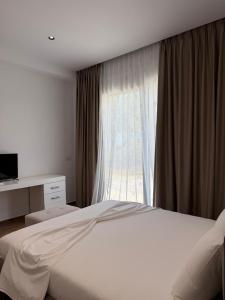 a bedroom with a white bed and a window at Blue Days Villa 2 in Shkalle Stenojt