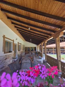 a patio with wicker chairs and purple flowers at Cuib de Munte in Brezoi +5 photos