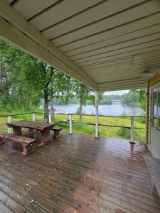 a covered deck with a picnic table and a lake at Linnansalmi Lakeside Villa with Sauna in Savonlinna