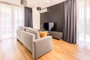 a living room with a couch and a tv at Baltic Season Spa Apartments in Grzybowo