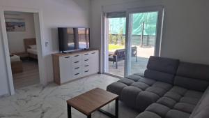 a living room with a couch and a tv at Mima apartments in Povljana