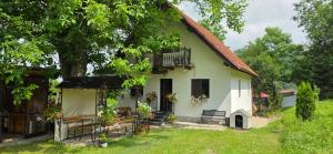 a white house with a tree and a balcony at Pilisca Holiday Home in Dobîrlău